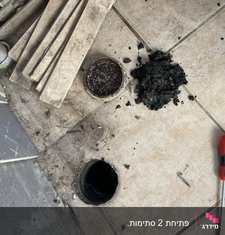 פתח ביוב פתוח עם לכלוך ומברג על הרצפה